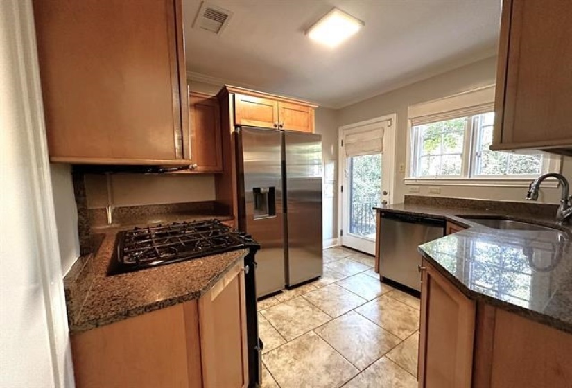 Kitchen with stainless steel appliances, dark stone counters, and light tile patterned flooring