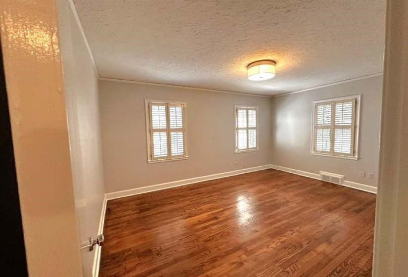 Wood finished floors, a textured ceiling, and crown molding
