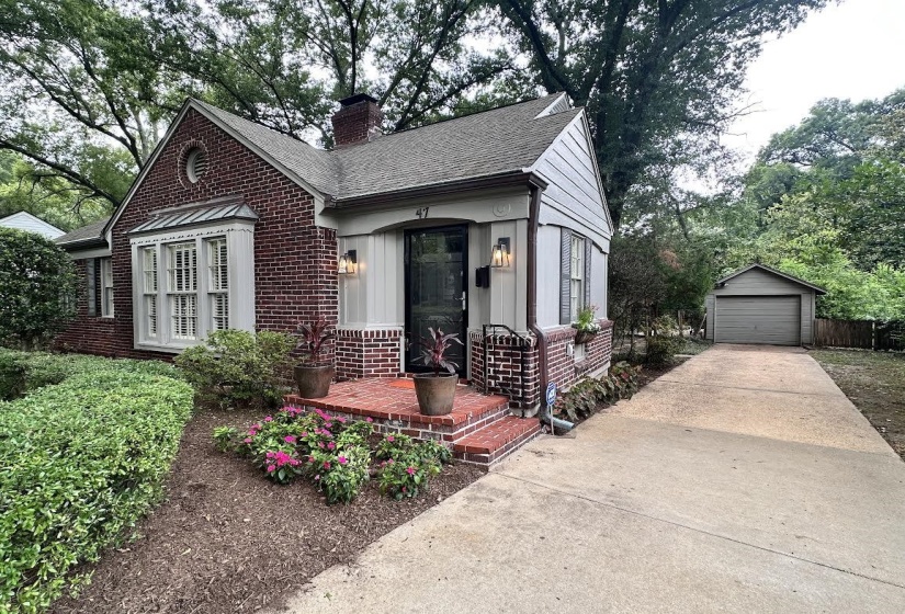 View of front of house with brick siding, an outbuilding, a garage, a chimney, and a shingled roof