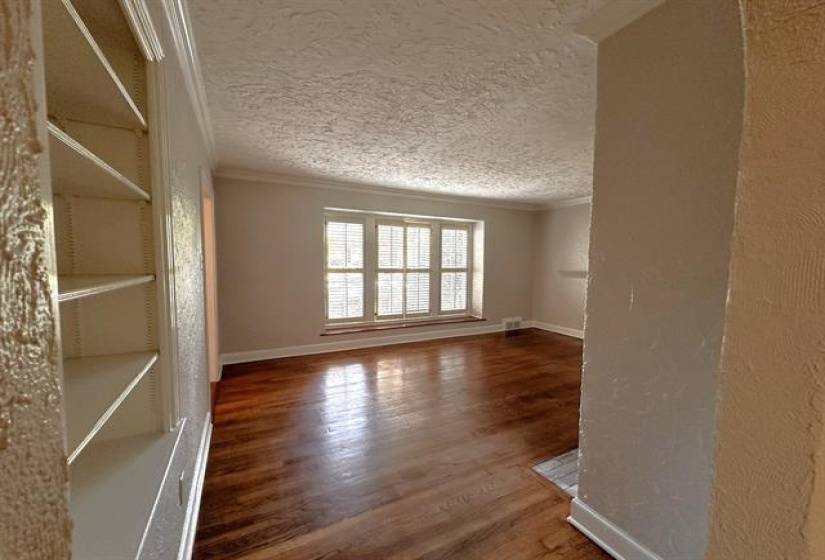 Empty room with wood finished floors, crown molding, a textured ceiling, and a textured wall