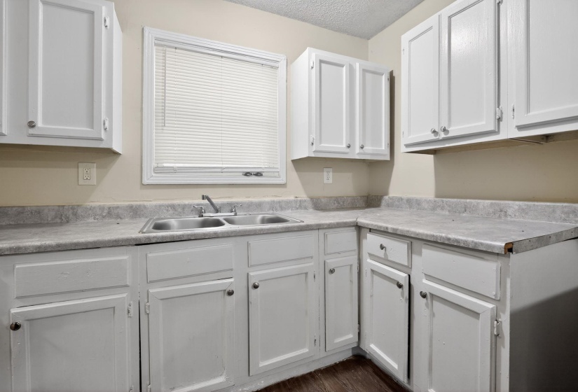 Kitchen featuring white cabinets, light countertops, a textured ceiling, and dark wood-style floors