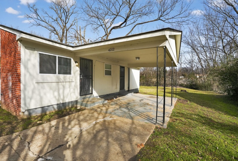 Rear view of property with an attached carport, driveway, and brick siding