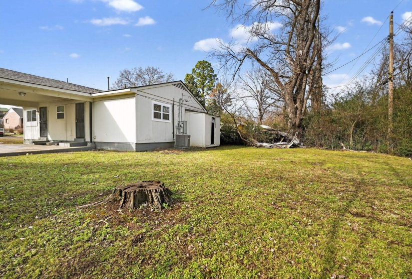 View of grassy yard with an attached carport and a patio