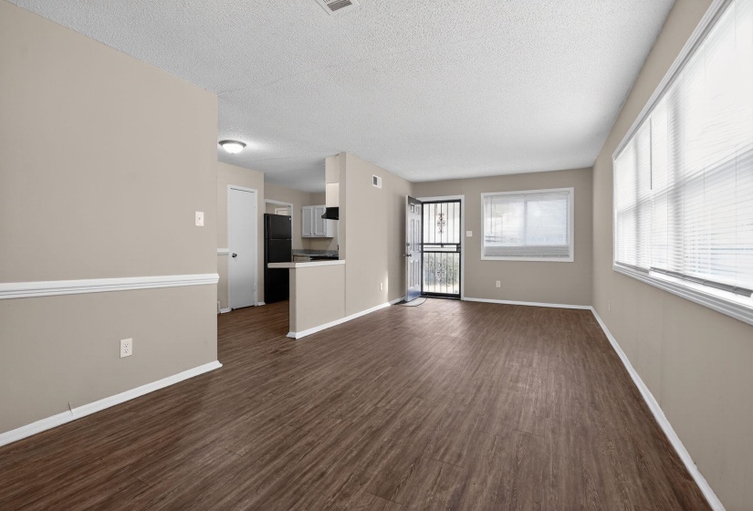 Unfurnished living room featuring dark wood-type flooring and a textured ceiling