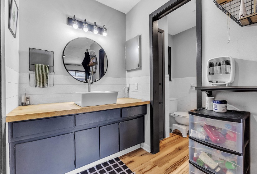 Bathroom with wainscoting, vanity, toilet, tile walls, and wood finished floors
