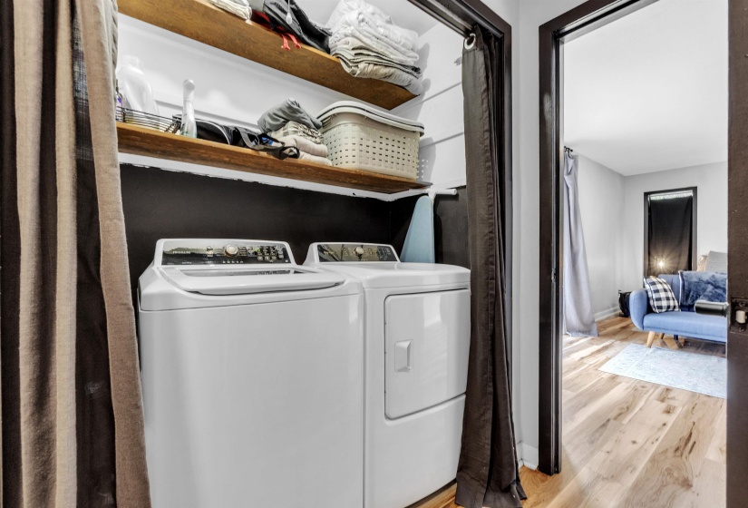 Washroom featuring laundry area, light wood finished floors, baseboards, and washer and dryer