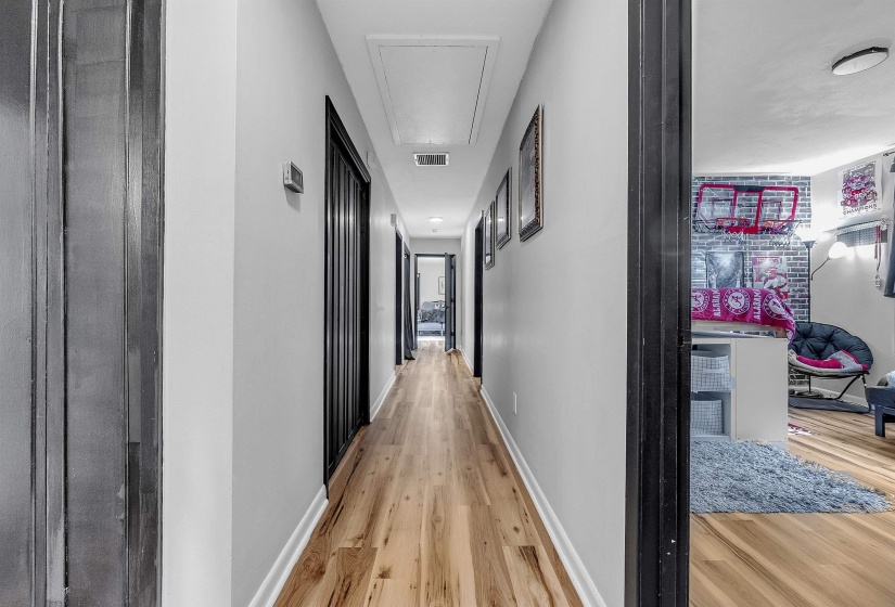 Corridor with baseboards, attic access, light wood-style flooring, and visible vents