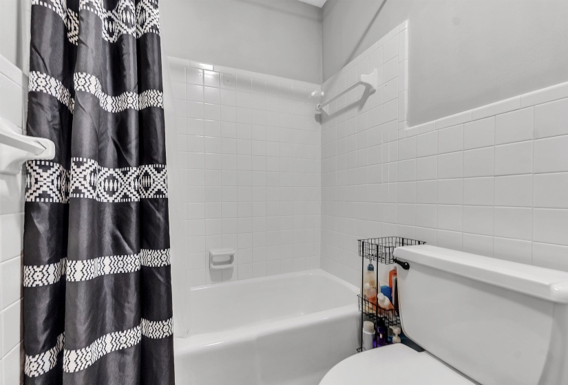 Bathroom featuring toilet, tile walls, and shower / tub combo with curtain