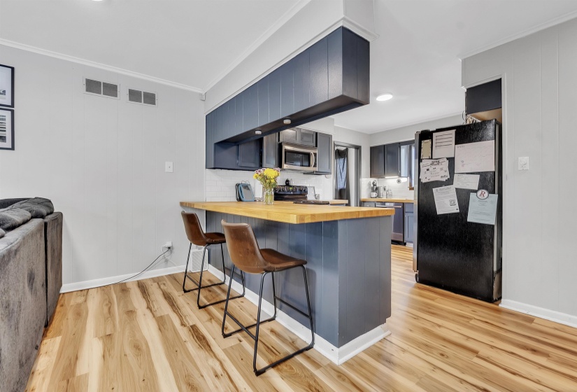 Kitchen featuring visible vents, appliances with stainless steel finishes, a breakfast bar area, and wooden counters