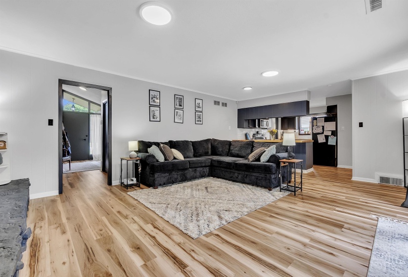 Living room with visible vents, light wood finished floors, crown molding, and baseboards