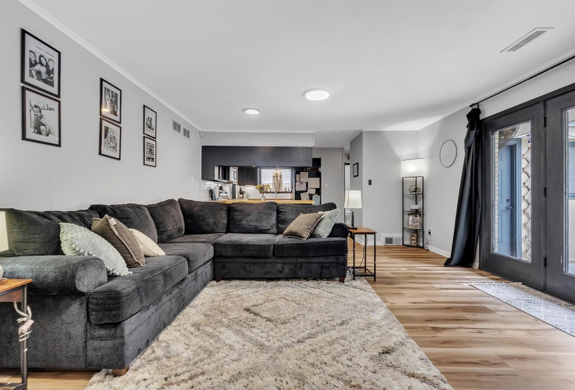 Living room featuring baseboards, visible vents, ornamental molding, and light wood-type flooring
