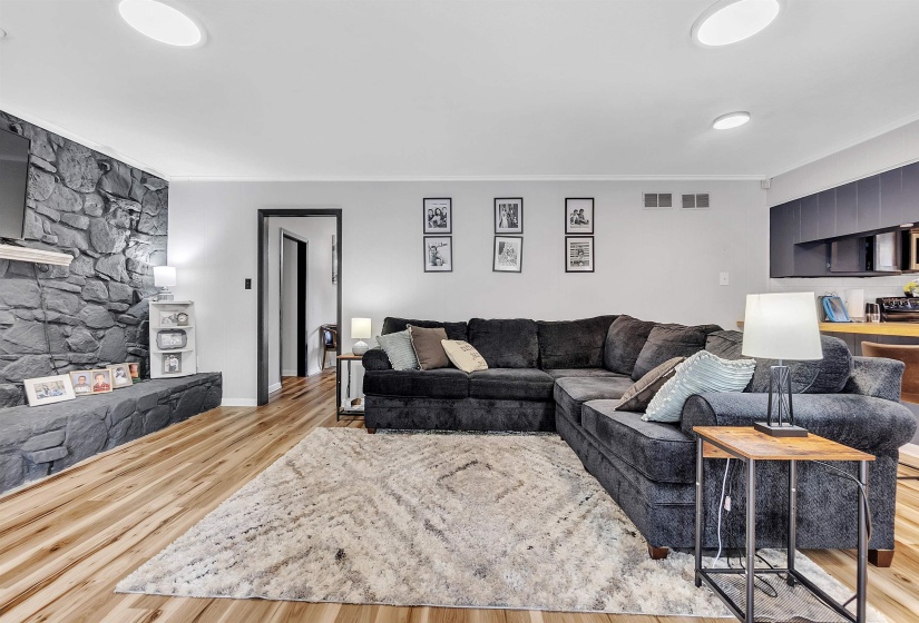 Living area featuring crown molding, baseboards, wood finished floors, and visible vents
