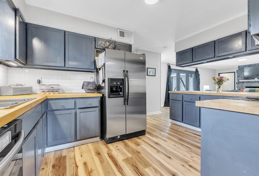 Kitchen with visible vents, decorative backsplash, stainless steel fridge, light wood-type flooring, and wood counters