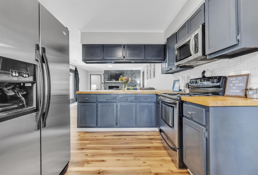 Kitchen with backsplash, stainless steel appliances, light wood-style flooring, and a peninsula