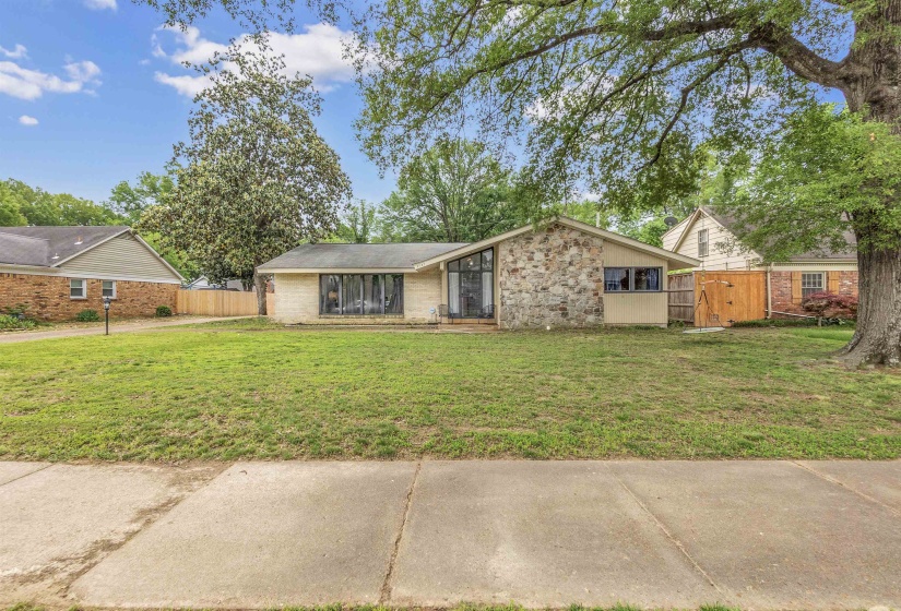 View of front facade with stone siding, fence, a gate, and a front yard