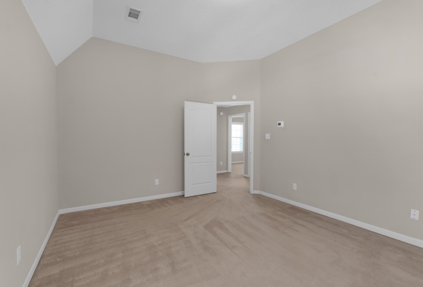 Empty room with light carpet and lofted ceiling