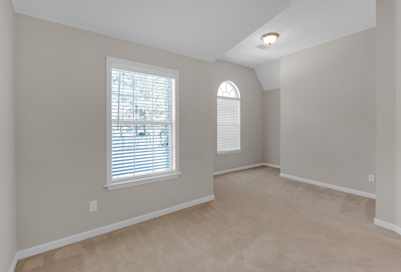Unfurnished room with light carpet and lofted ceiling