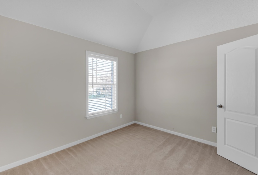 Spare room featuring light carpet and vaulted ceiling