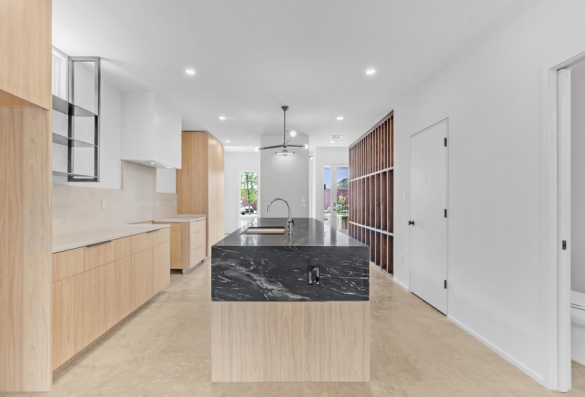Kitchen featuring modern cabinets, light brown cabinetry, a sink, an island with sink, and finished concrete flooring