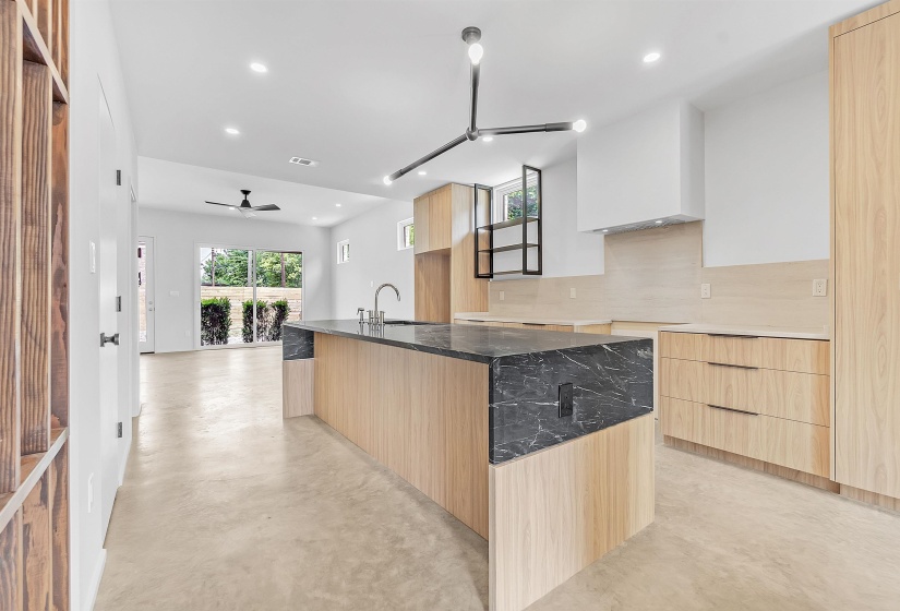 Kitchen featuring light brown cabinets, modern cabinets, recessed lighting, an island with sink, and decorative backsplash