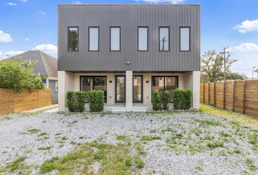 View of front of house featuring brick siding, a fenced backyard, and a patio