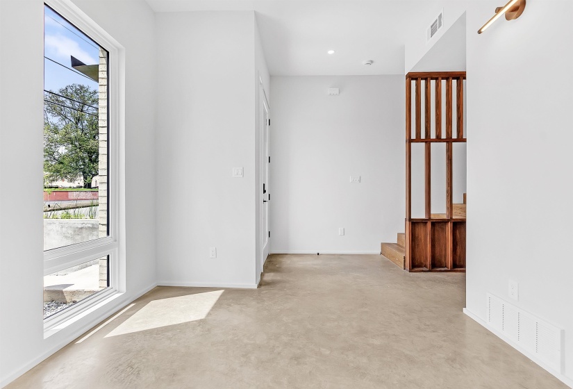 Spare room featuring finished concrete floors, healthy amount of natural light, baseboards, and stairway