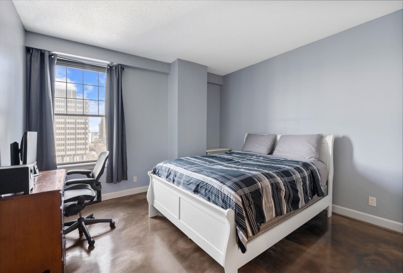 Bedroom featuring concrete flooring and a desk