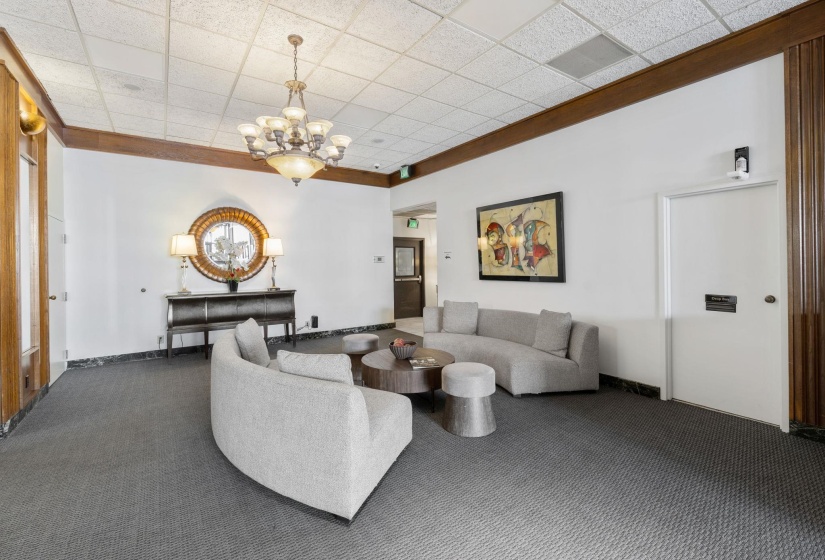 Living area with carpet, hanging lights, and a paneled ceiling
