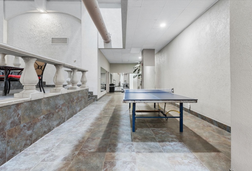 Game room featuring a textured wall, recessed lighting, and a high drop ceiling