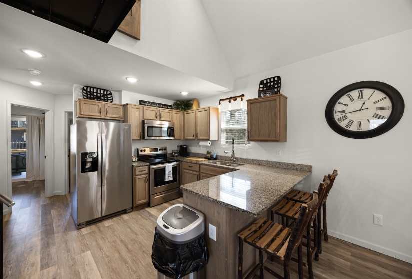 Kitchen featuring a kitchen breakfast bar, stainless steel appliances, a sink, light wood-style flooring, and a peninsula