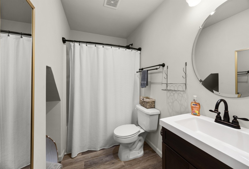 Bathroom featuring wood finished floors, vanity, toilet, and visible vents