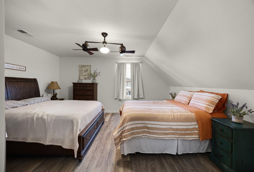 Bedroom featuring lofted ceiling, visible vents, a ceiling fan, and wood finished floors