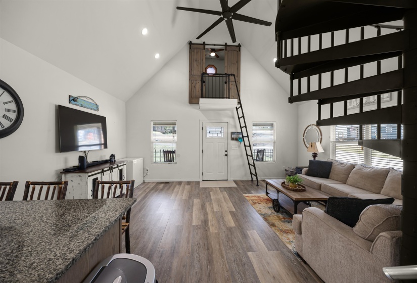 Living area with high vaulted ceiling, ceiling fan, wood finished floors, and a wealth of natural light