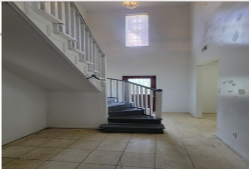 Entryway featuring stairway, a high ceiling, and light tile patterned flooring