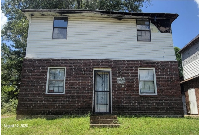 View of front of property with brick siding and a front lawn