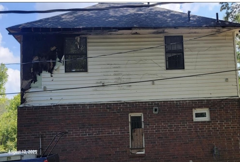 View of side of home with a shingled roof and brick siding
