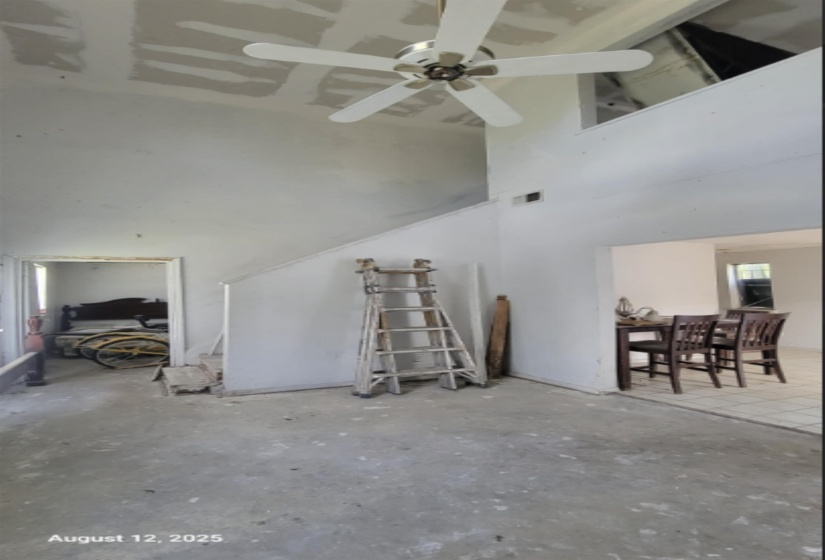 Living area featuring unfinished concrete floors, a high ceiling, and ceiling fan