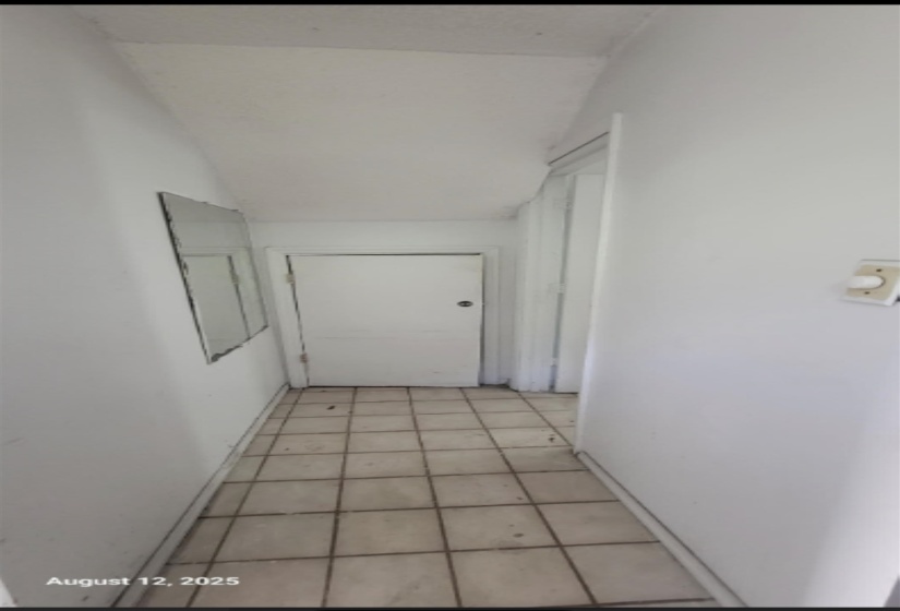 Corridor with vaulted ceiling and light tile patterned flooring