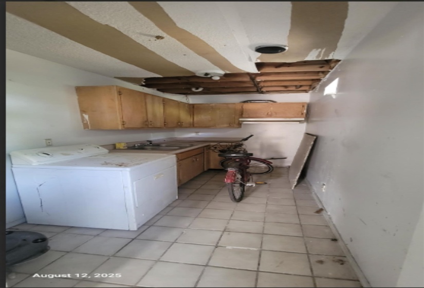 Kitchen with washer / dryer, light countertops, and light tile patterned floors