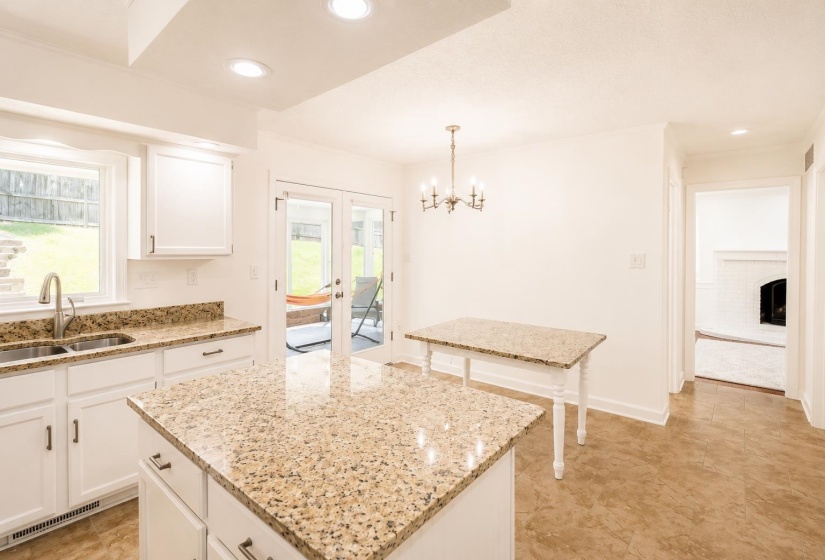 Kitchen featuring white cabinetry with dark hardware, a center island with a stone countertop, and a double-basin sink