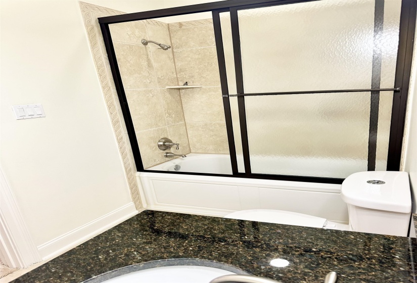 Bathroom featuring bath / shower combo with glass door and toilet