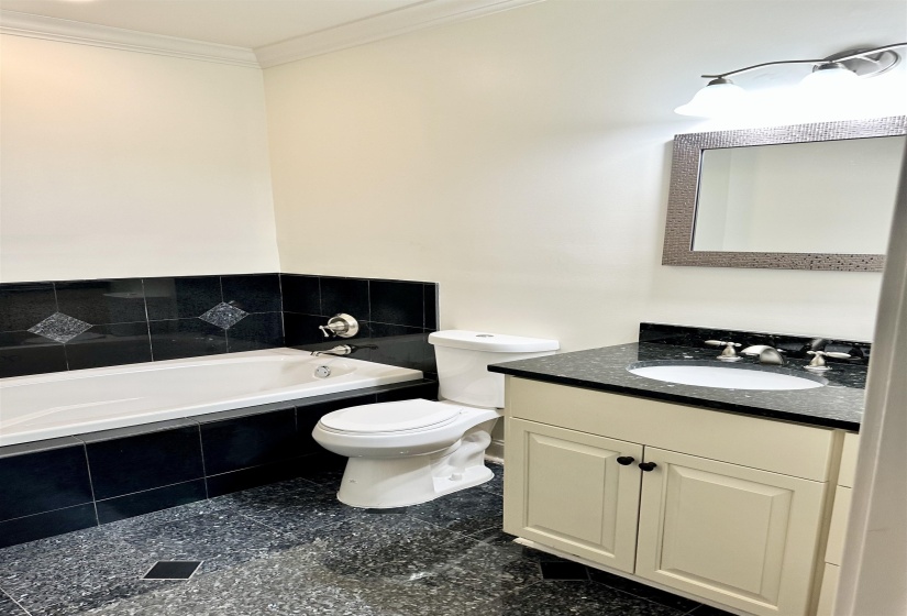 Bathroom with crown molding, tiled bath, vanity, and toilet
