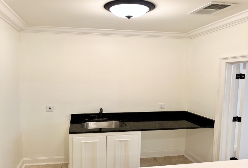Interior space featuring ornamental molding, light tile patterned flooring, and sink