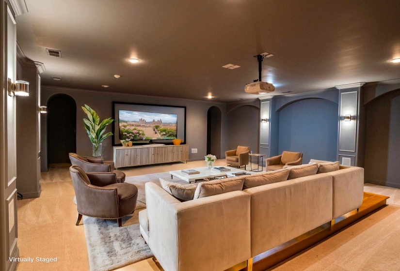 Home theater room featuring light colored carpet, visible vents, arched walkways, recessed lighting, and ornate columns