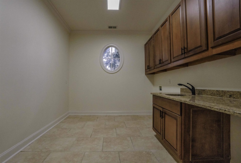 Clothes washing area with washer hookup, light tile patterned flooring, ornamental molding, sink, and cabinets