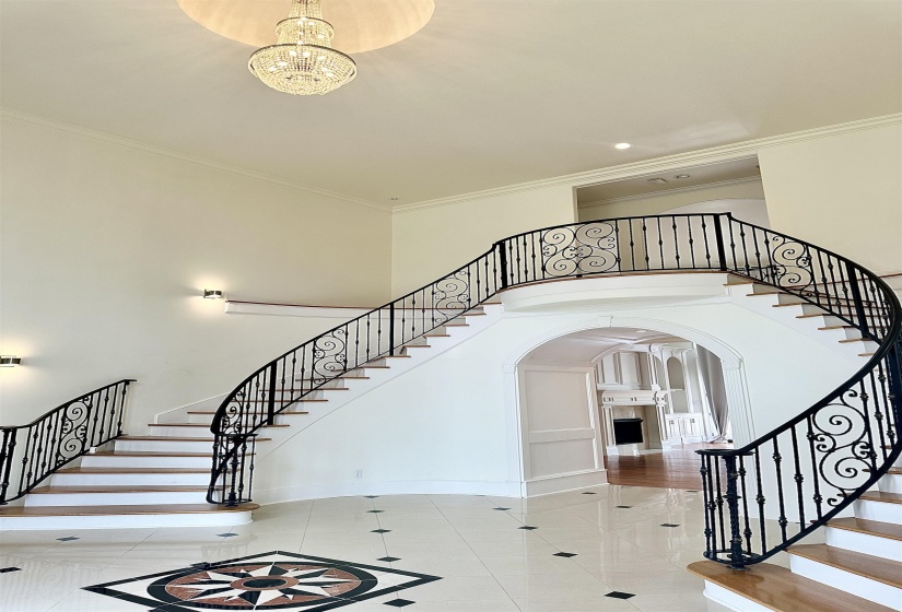 Stairway featuring a notable chandelier, crown molding, arched walkways, and a high ceiling