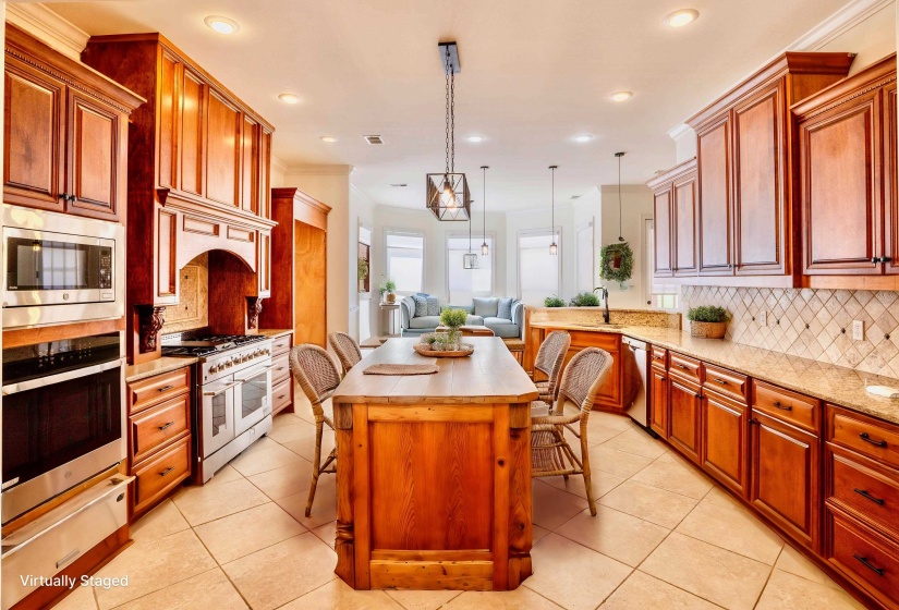 Kitchen featuring decorative backsplash, light tile patterned flooring, a breakfast bar, appliances with stainless steel finishes, and open floor plan