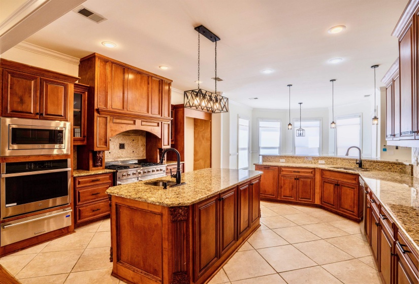 Kitchen with an island with sink, stainless steel appliances, decorative light fixtures, and sink