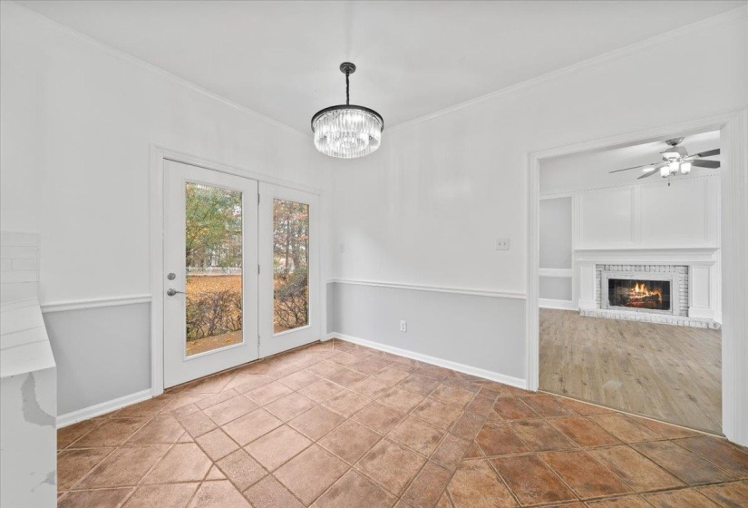 Unfurnished dining area featuring a fireplace, ornamental molding, a ceiling fan, and a chandelier