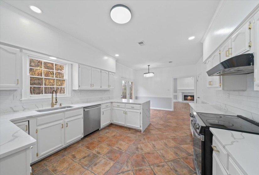 Kitchen with backsplash, black / electric stove, light stone counters, a warm lit fireplace, and recessed lighting